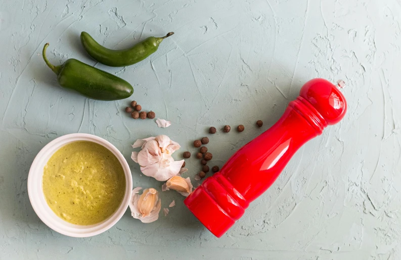 a pepper shaker sitting on top of a table next to a bowl of sauce, inspired by Ceferí Olivé, trending on pexels, green bright red, product image, solid background, ingredients on the table