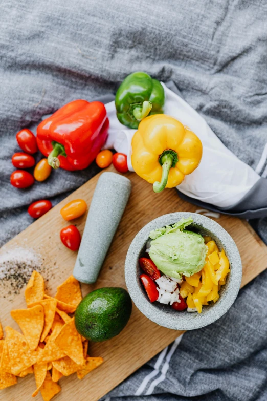 a wooden cutting board topped with chips and vegetables, inspired by Diego Rivera, pexels contest winner, avacado chairs, breakfast, cloth wraps, mortar and pestle