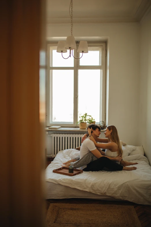 two woman in white shirts sitting on top of a bed