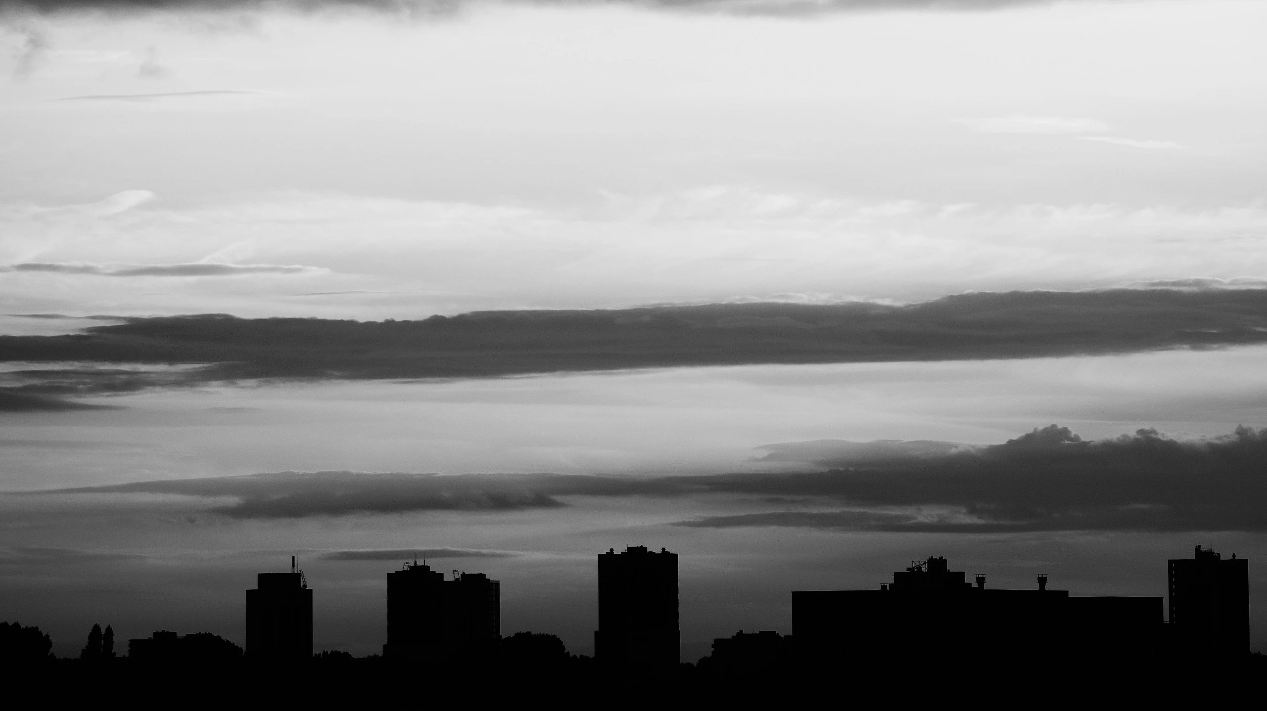 a black and white photo of a city skyline, a black and white photo, minimalism, cloudy sunset, valeriy vegera, silhouette :7