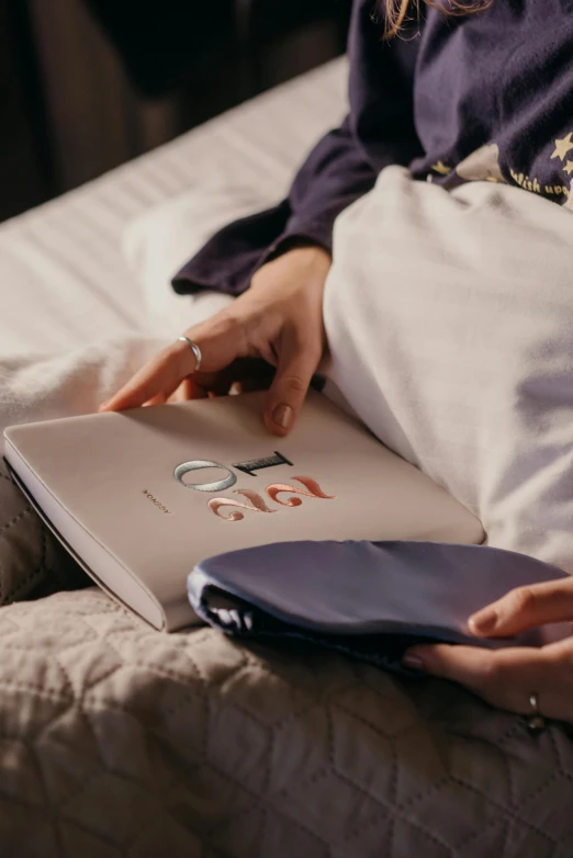 a woman is sitting on the bed holding her purse