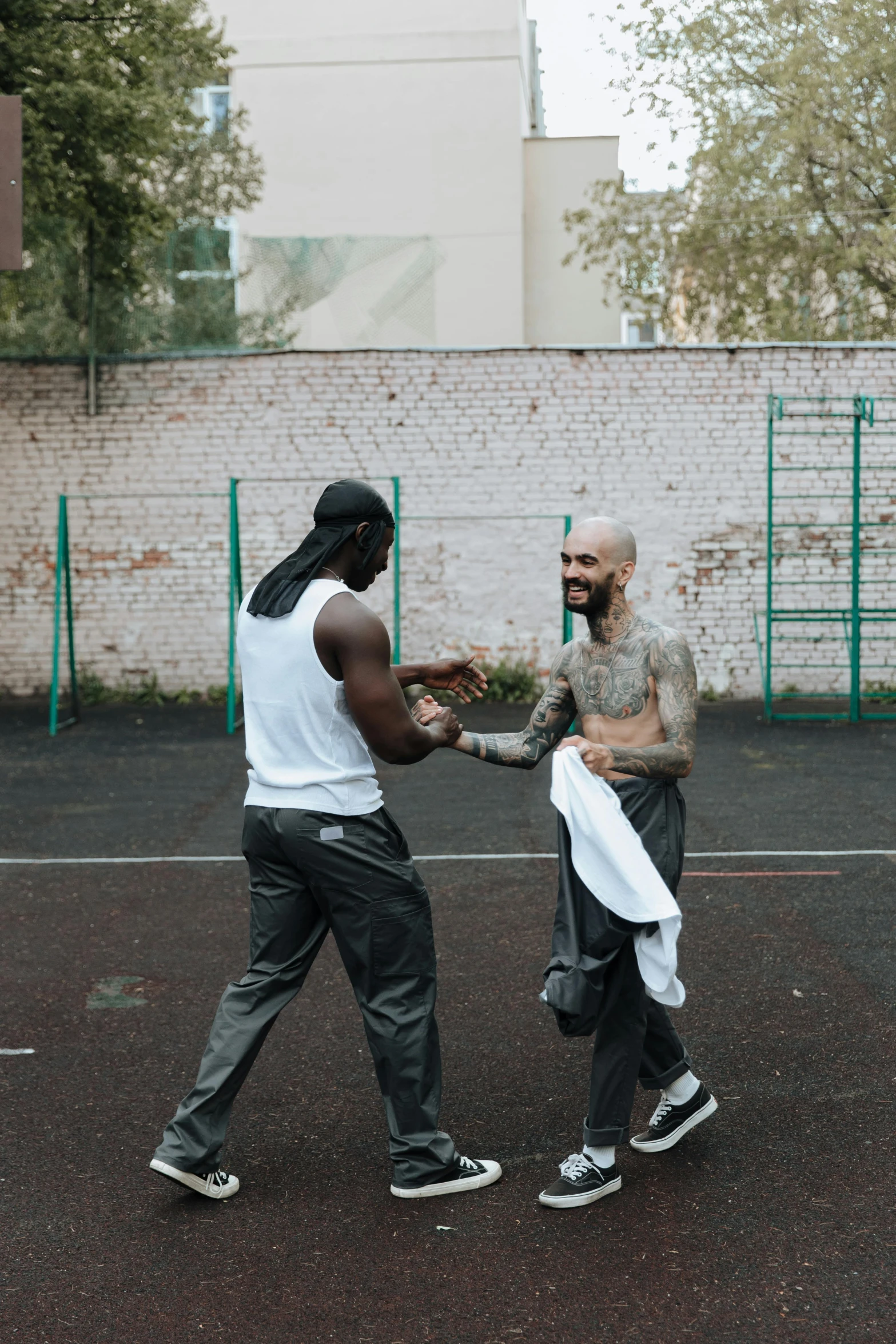 two men shaking hands on a tennis court, an album cover, by Matija Jama, pexels contest winner, street art, arms covered in gang tattoo, offwhite, kevin garnett, local gym