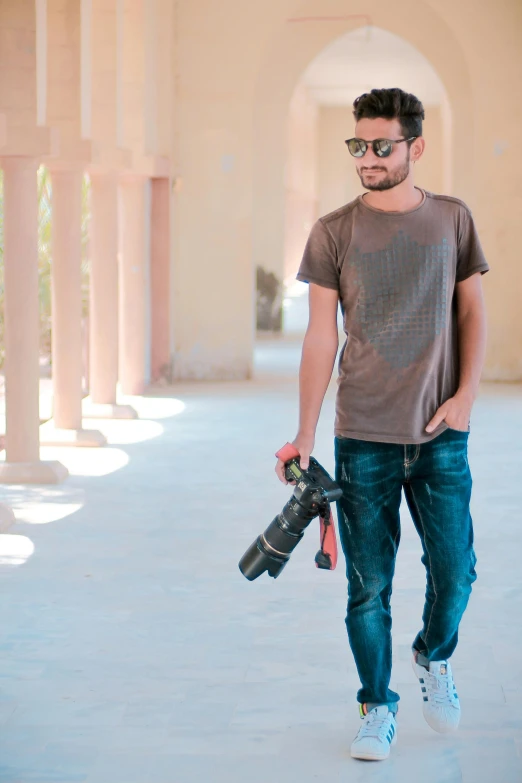 a man with sunglasses holding a camera and a backpack