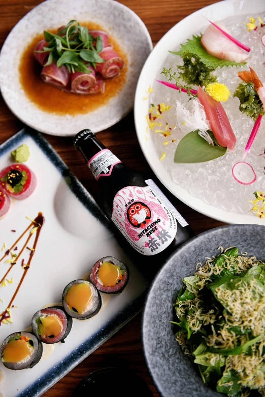 a table topped with plates of food and a bottle of beer, inspired by Miyagawa Chōshun, unsplash, mingei, pink, lush sakura, chefs table, high angle close up shot