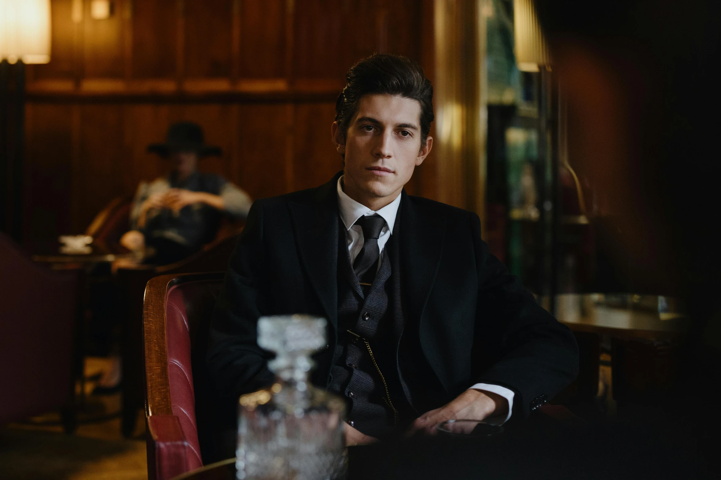 a man in a suit sitting at a table, unsplash, renaissance, costumes from peaky blinders, american gods, “portrait of leonard cohen, young man