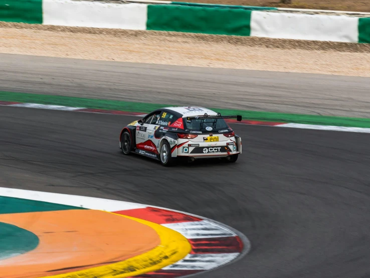 a racing car driving around a track with grass and trees around it