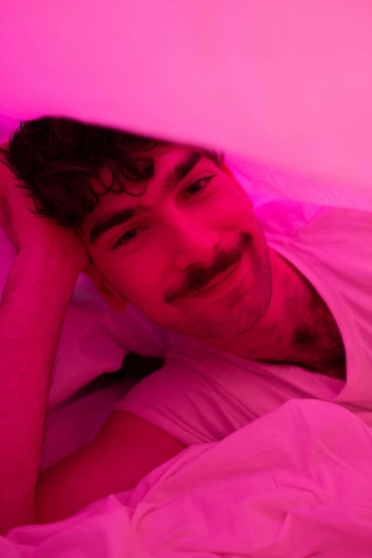 a man with a mustache laying in a bed under the covers