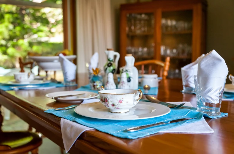 a wooden table with white dishes and blue napkins