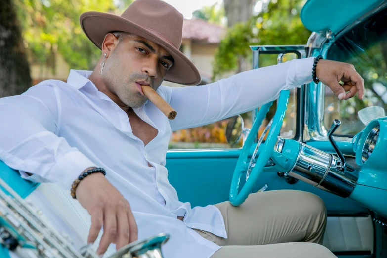 a man sitting in the back of an old blue car