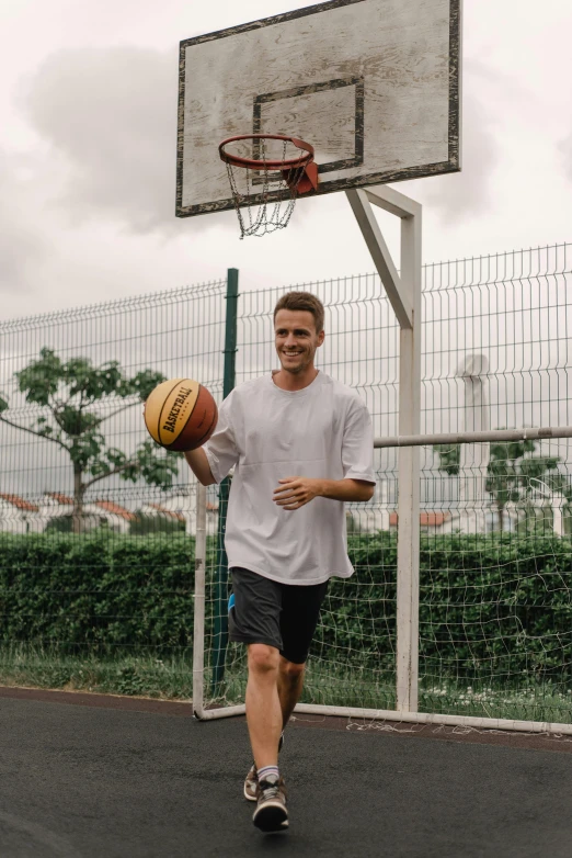 a man holding a basketball on a basketball court, singapore ( 2 0 1 8 ), athletic tall handsome guys, carson ellis, in shorts