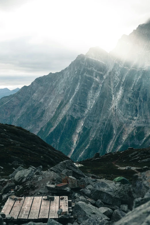 an empty picnic table sits on the rocky bank above mountains