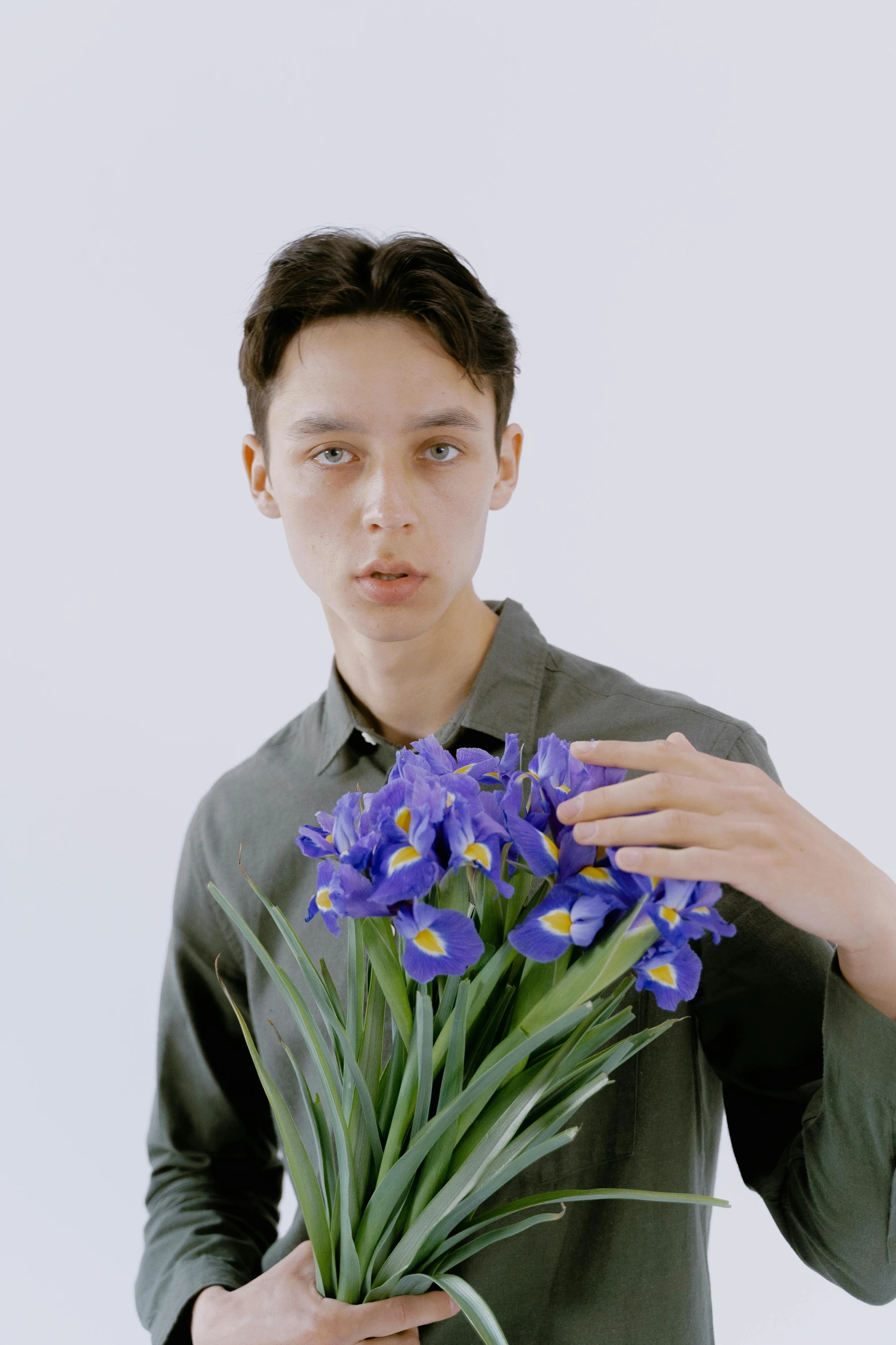 a man holding a bunch of purple flowers, an album cover, inspired by Jean Malouel, unsplash, hyperrealism, iris compiet, ignant, video, delicate androgynous prince