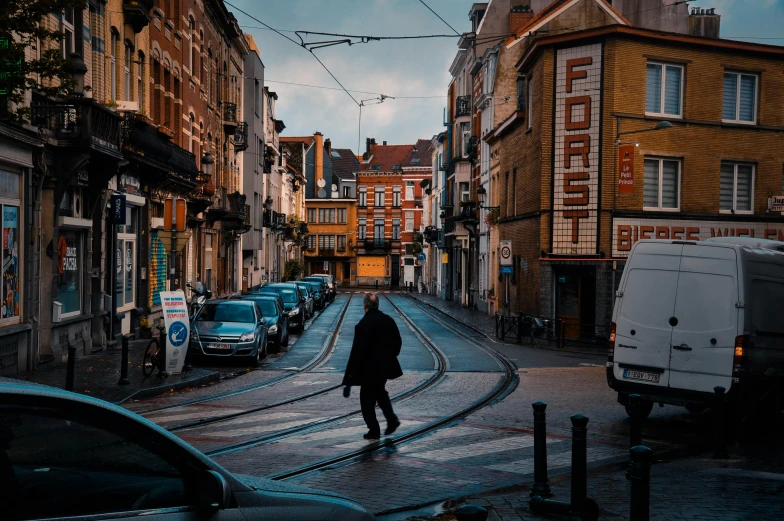 a man walking down a street next to tall buildings, a photo, by Jan Tengnagel, pexels contest winner, renaissance, liege, trams ) ) ), busy small town street, street of teal stone