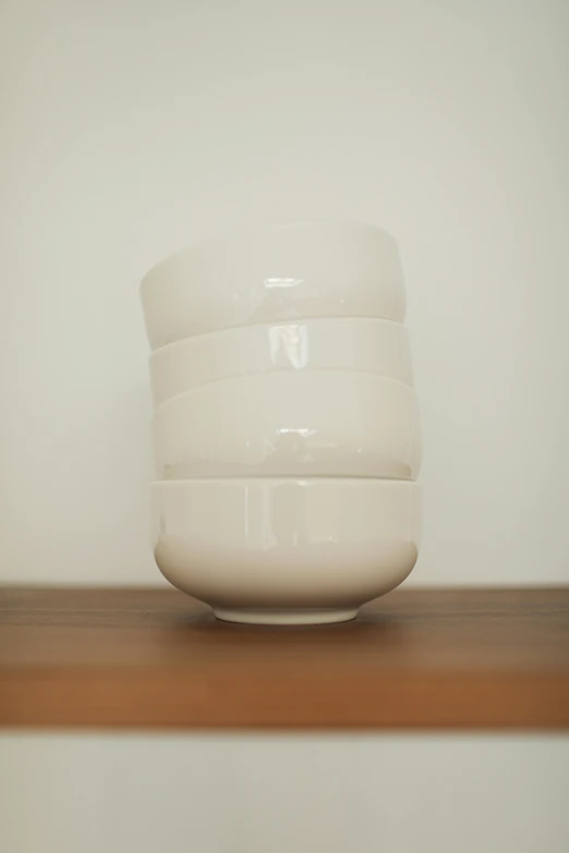 a white bowl sitting on top of a wooden table, inspired by Jiro Yoshihara, minimalism, stacked, cream, hero shot, made of glazed