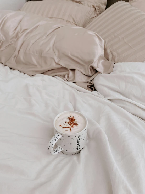 a cup on the bed with the covers pulled over