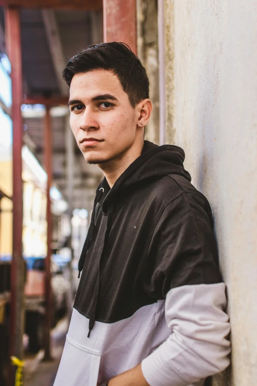 a young man leaning against a wall in the city