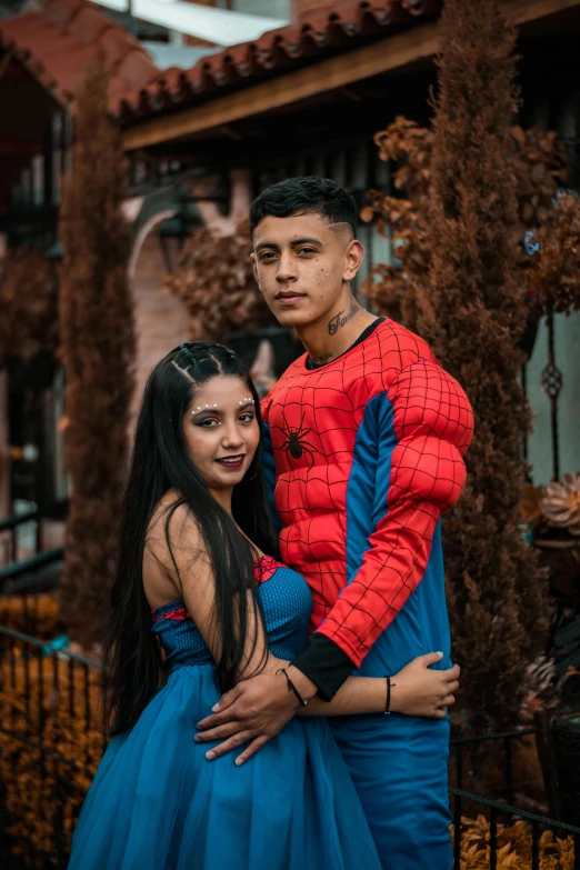 a man standing next to a woman in a blue dress, a colorized photo, by Alejandro Obregón, pexels contest winner, international gothic, portrait of spiderman, gif, 18 years old, peruvian looking