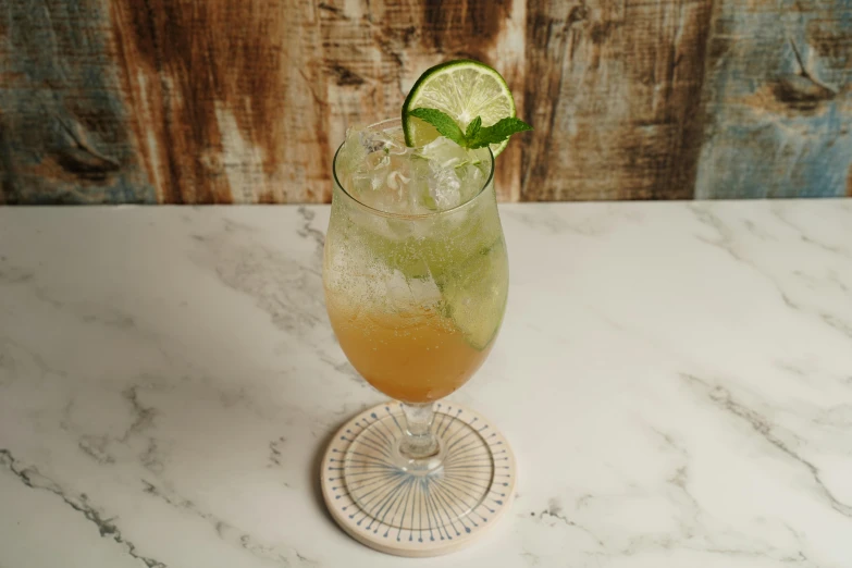 a close up of a drink in a glass on a table, on a marble pedestal, lime green, light tan, frontal pose