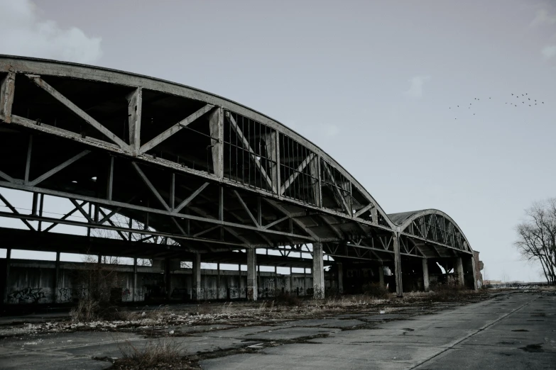 a black and white photo of a train bridge, inspired by Tsuchida Bakusen, pexels contest winner, brutalism, post apocalyptic shopping center, rounded roof, cleveland, desolated wasteland