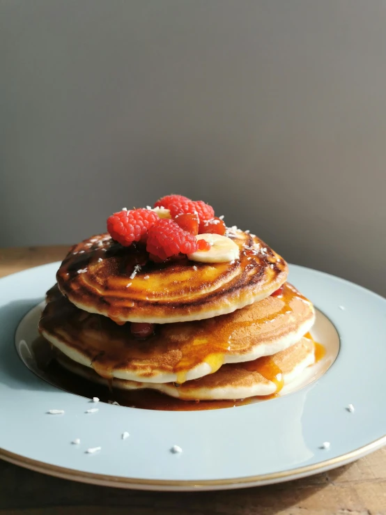 a stack of pancakes topped with raspberries on top of a blue plate