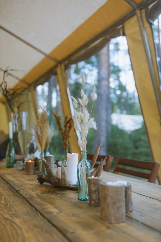 a wooden table topped with vases filled with flowers, unsplash, interior of a tent, finland, close-up, brown