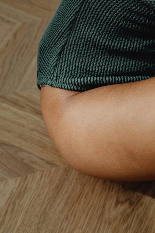 a person sitting on the floor with a cell phone in their hand, olive thigh skin, zoomed in, from the elbow, light-brown skin