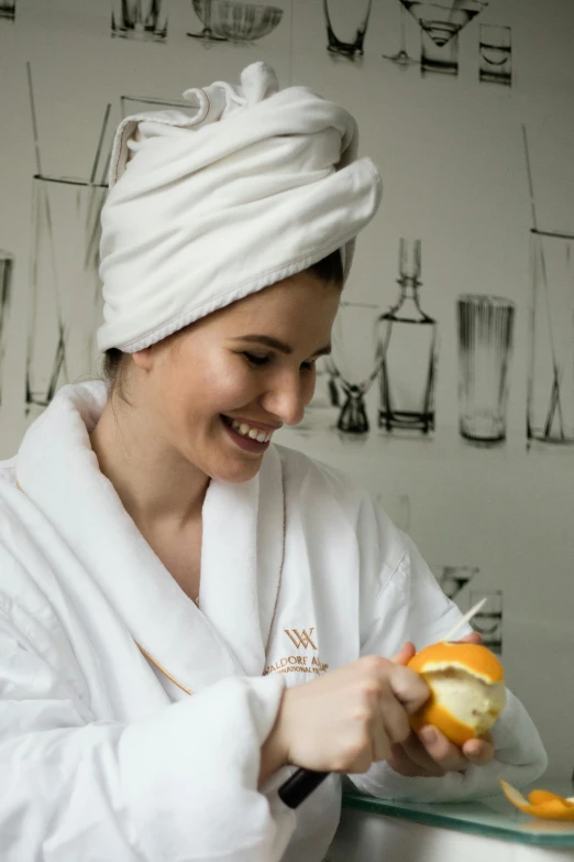 a woman in a bathrobe is peeling an orange, a portrait, unsplash, turning her head and smiling, michal, low quality photo, ewa juszkiewicz