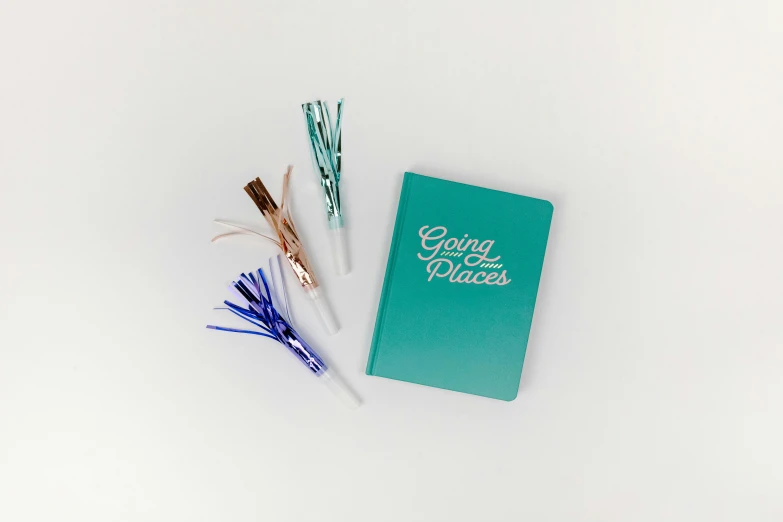 a green book sitting on top of a white table, white and teal metallic accents, glow sticks, oh the places you'll go, high res photograph