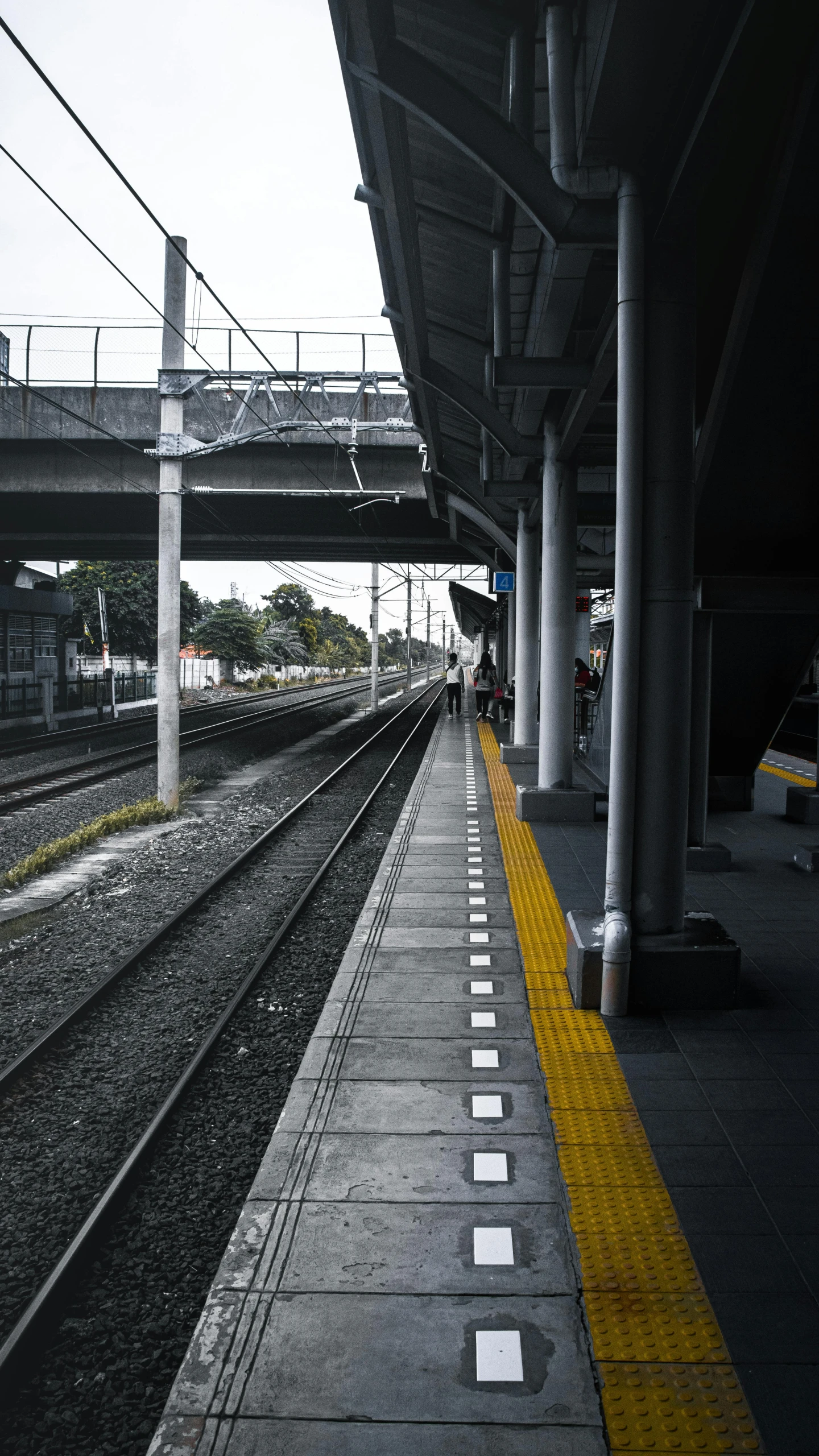 a train station with the tracks visible under a pedestrian bridge