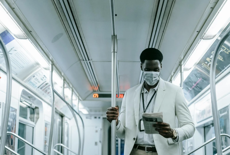 a man standing on a subway holding a newspaper, pexels contest winner, afrofuturism, with a lab coat, worksafe. instagram photo, passengers, wearing white suit