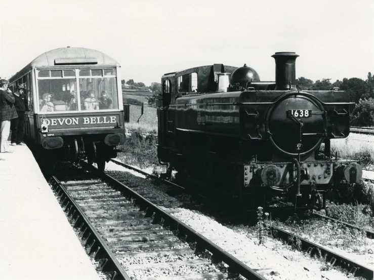 a black and white photo of a train pulling into a station, a black and white photo, private press, belle, devon cady-lee, front and side view, archive photo