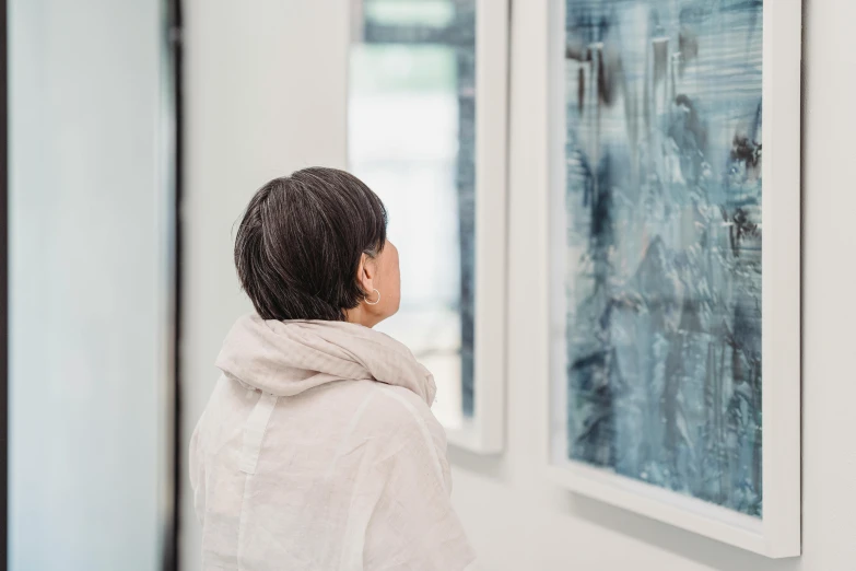 a woman looking at paintings on a wall, by Richter, trending on unsplash, visual art, katsuhika hokusai, profile image, looking through frosted glass, over-shoulder shot