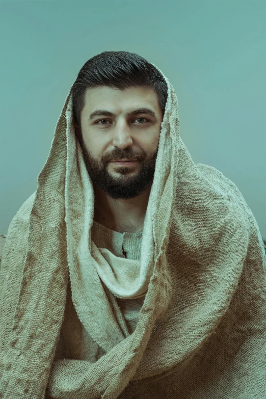 a man wrapped in blanket smiling at the camera