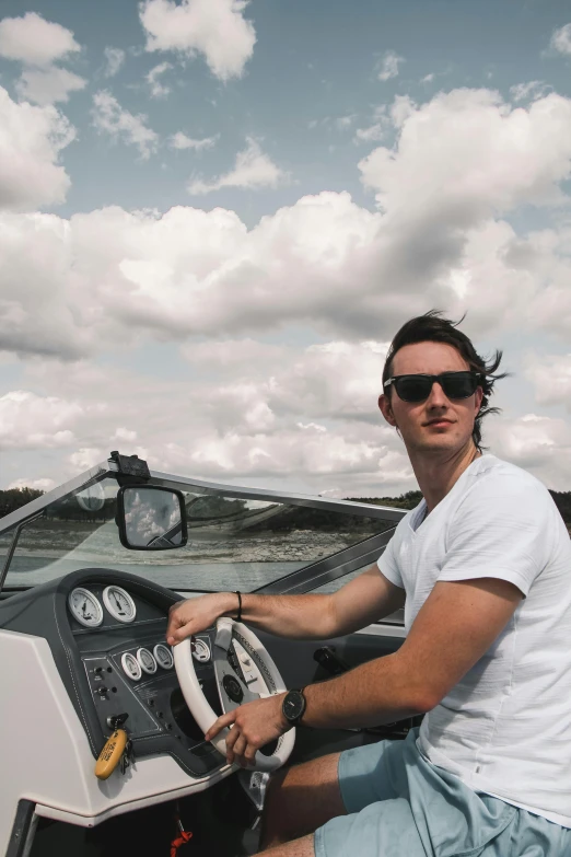 a man sitting in the driver's seat of a boat, pexels contest winner, looking hot, sydney hanson, clouds around, low quality photo