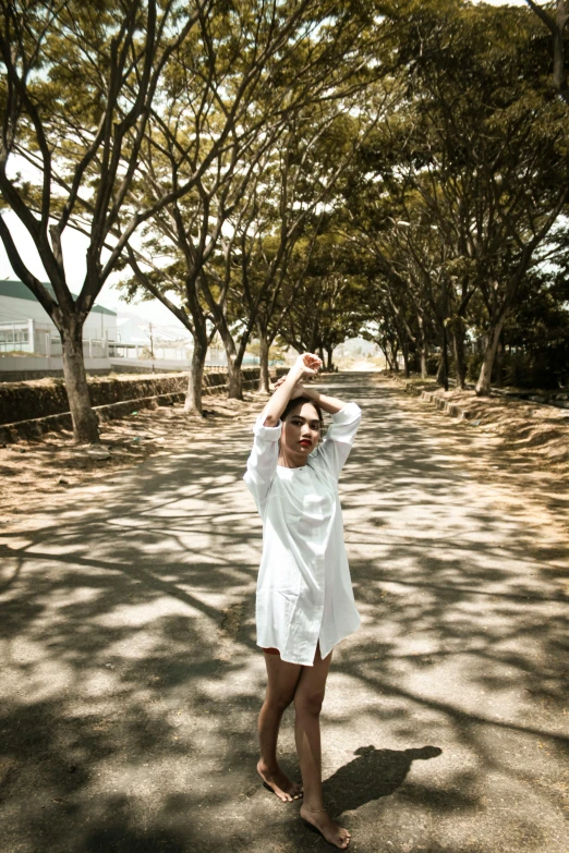 a woman standing in the middle of a road holding a frisbee, inspired by Ren Hang, unsplash, happening, wearing a white hospital gown, in garden, 8 k ), satisfied pose