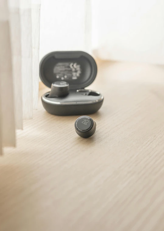 a pair of ear buds sitting on top of a wooden floor, hammershøi, grey, facing away, small in size