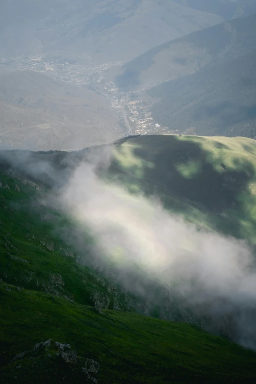 a hilly mountain view has mist on the top