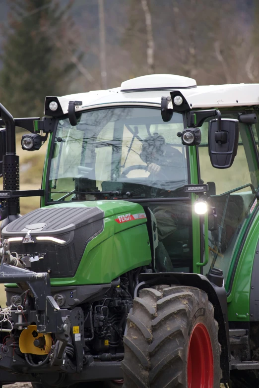 a green tractor driving down a dirt road, by Werner Gutzeit, shutterstock, glass oled visor head, front light, square, european