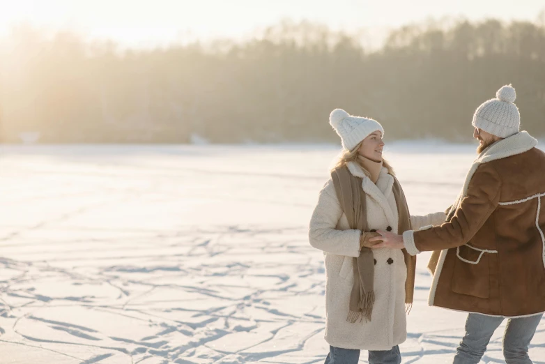 a couple of people standing on top of a snow covered field, trending on pexels, brown, winter lake setting, sparkling in the sunlight, scene from a movie