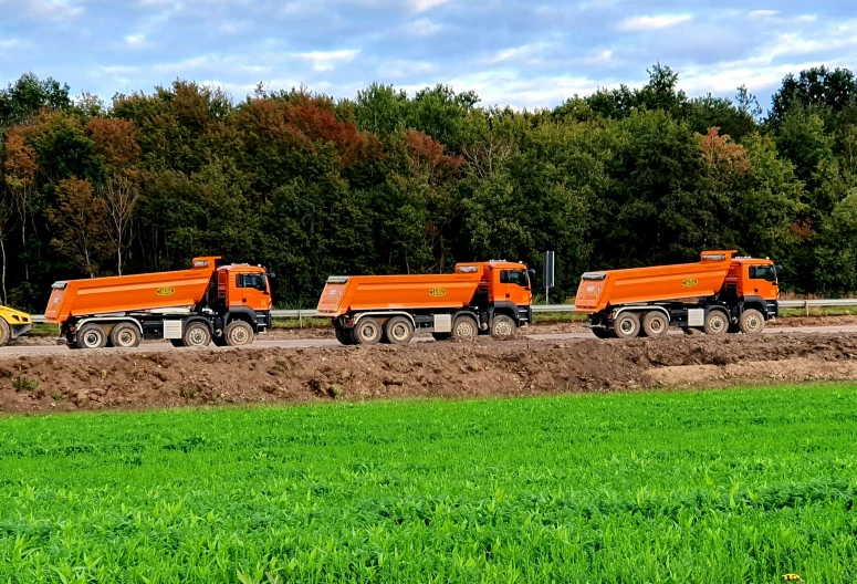 a group of dump trucks driving down a road, by Andries Stock, pixabay, arbeitsrat für kunst, green and orange theme, working out in the field, avatar image, no - text no - logo