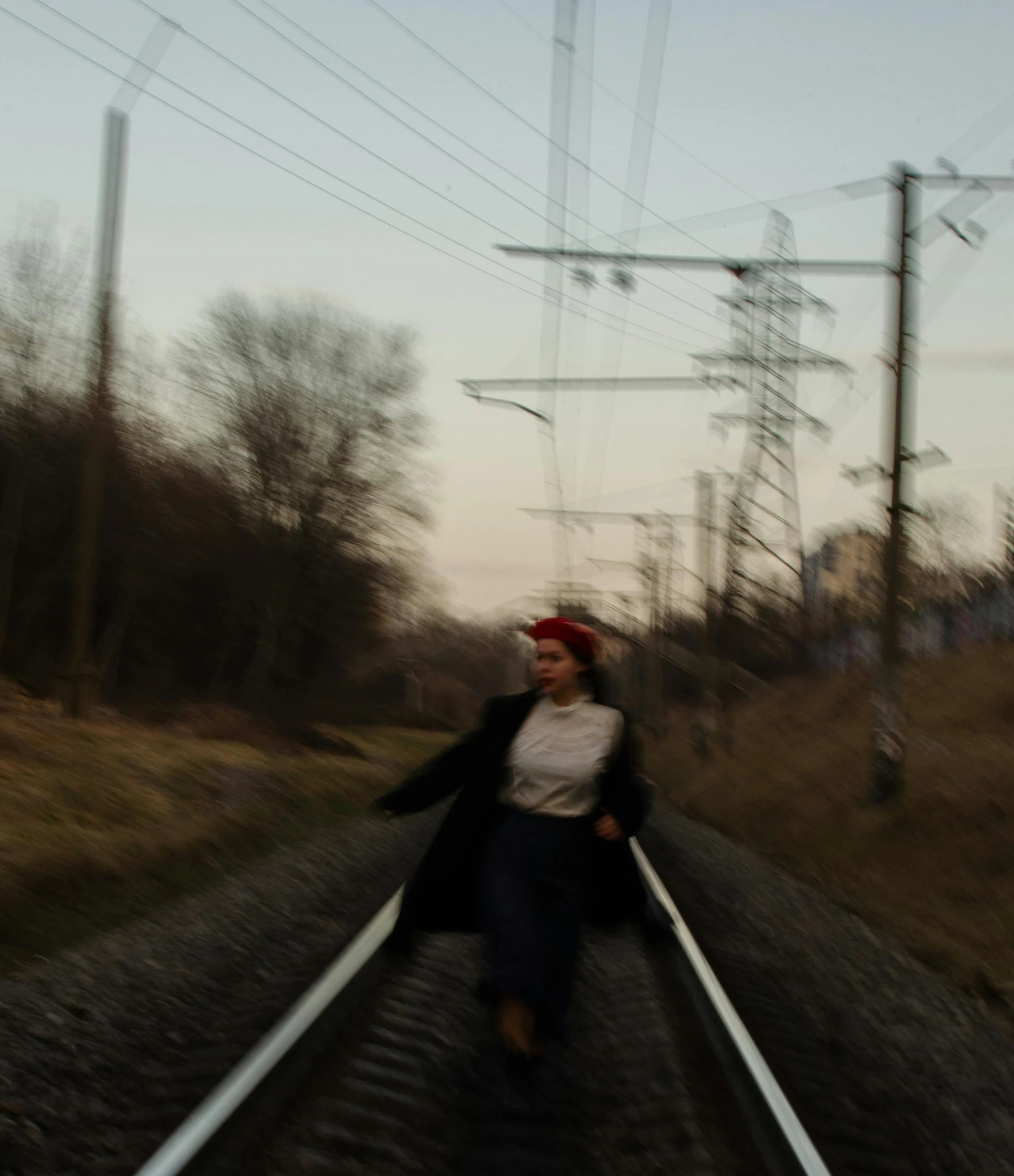 a woman in a black coat crossing train tracks