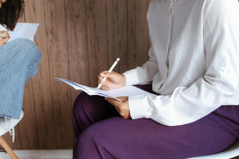 a man and a woman sitting next to each other, by Alice Mason, trending on unsplash, private press, holding a clipboard, white and purple, white hijab, pen on white paper