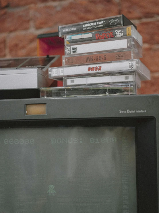 a stack of dvds sitting on top of a television, an album cover, inspired by Elsa Bleda, pexels, video art, cassette tape, 1987 photograph, old computers, 1999 photograph
