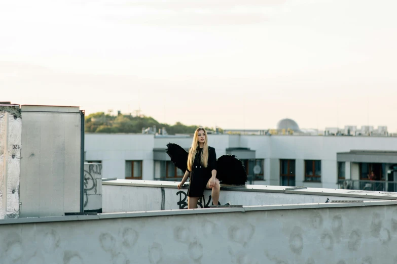 a woman sitting on the roof of a building, by Emma Andijewska, has black wings, blonde, cinematic shot ar 9:16 -n 6 -g, miro petrov