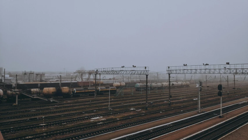 a train yard filled with lots of train tracks, a picture, inspired by Elsa Bleda, unsplash, under a gray foggy sky, azamat khairov, low quality photo, large scale photo