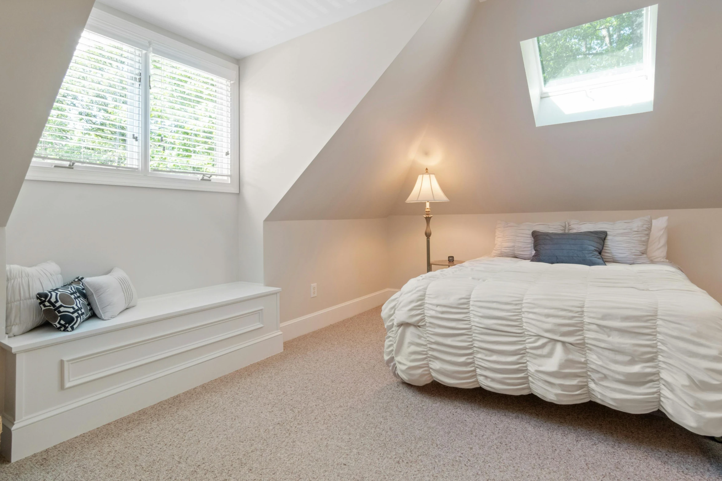 a large white bed sitting under a window in a bedroom