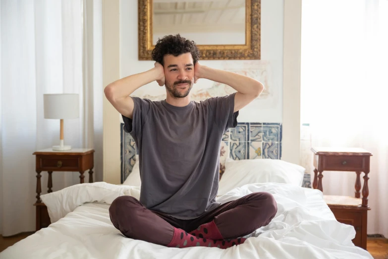 a man sitting on top of a bed with white sheets