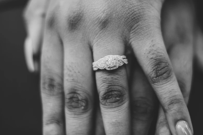 a close up of a person's hand with a ring on it, a black and white photo, pexels, romanticism, marriage, ornate with white diamonds, realistic »