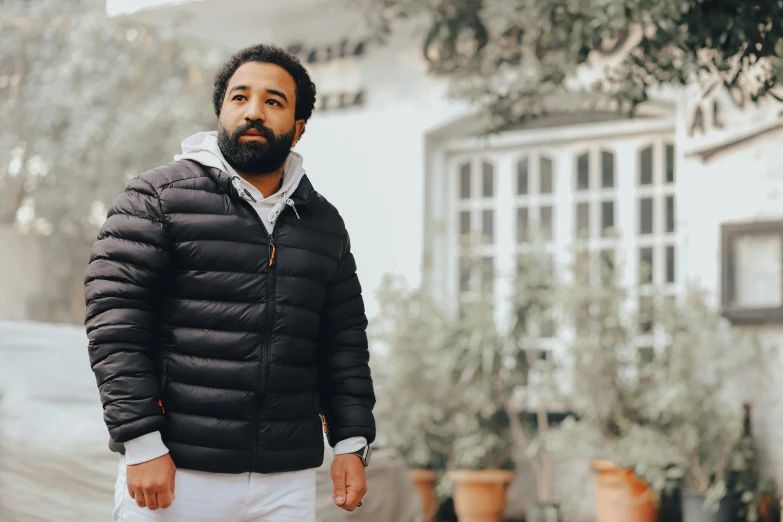 a man in a black jacket and white pants, inspired by Raúl Martínez, pexels contest winner, jeffrey wright, model wears a puffer jacket, nature outside, white backround