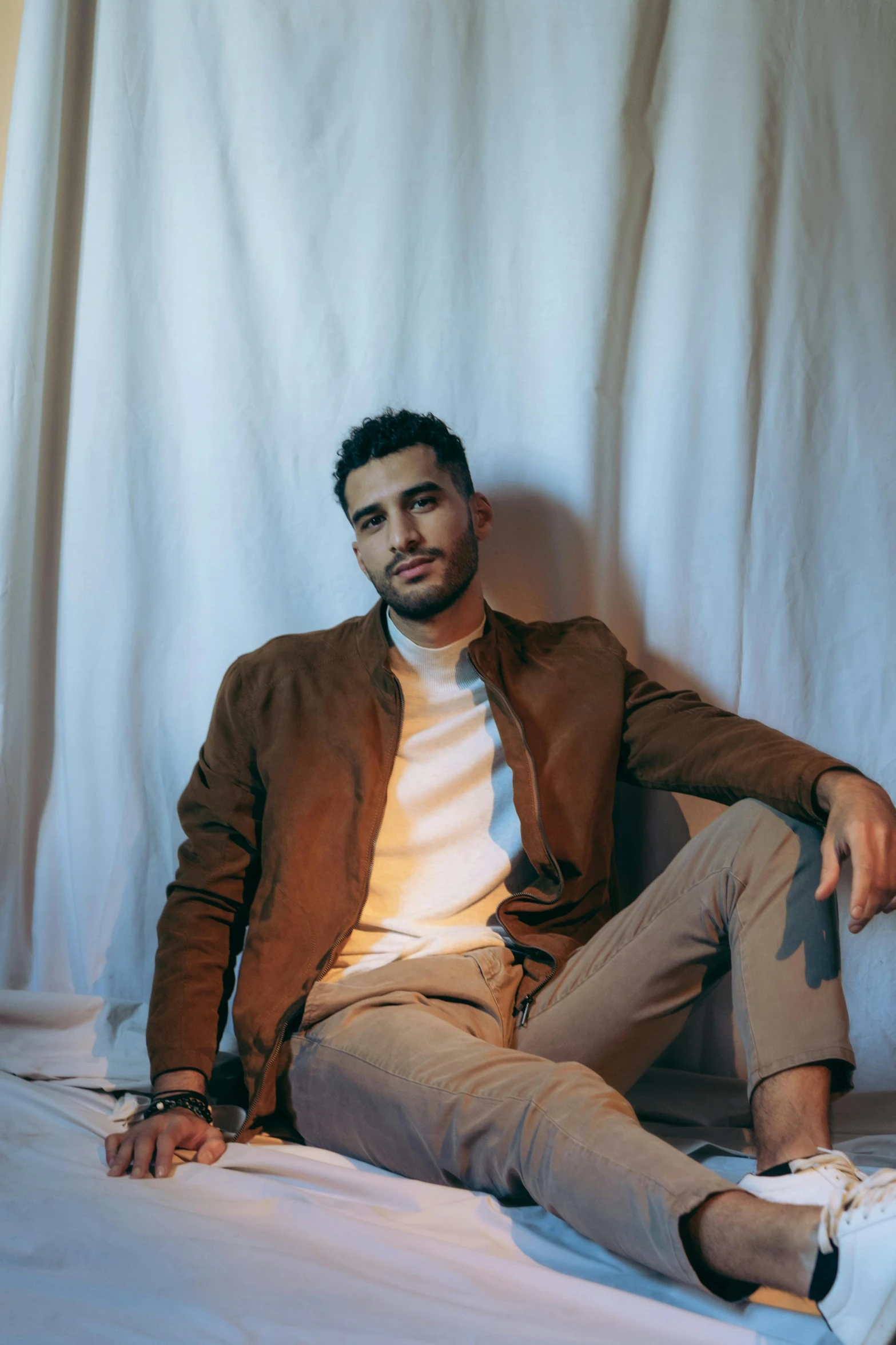 a young man in beige sitting on the bed